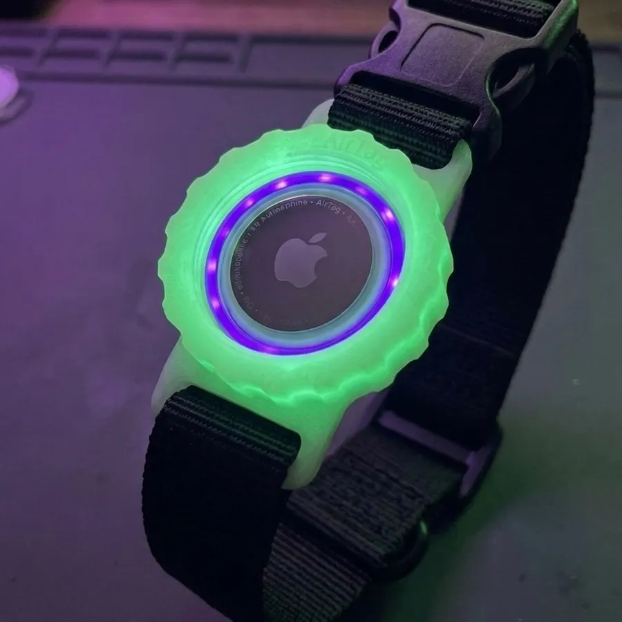 A glowing green 3D printed AirTag holder on a dog collar photographed in the dark