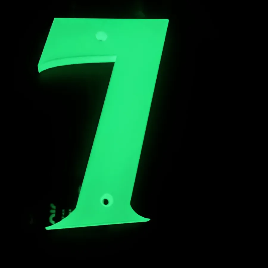 A glow in the dark 3D printed house number seven photographed in the dark